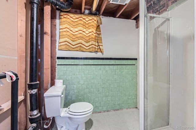 bathroom with toilet, tile walls, and walk in shower