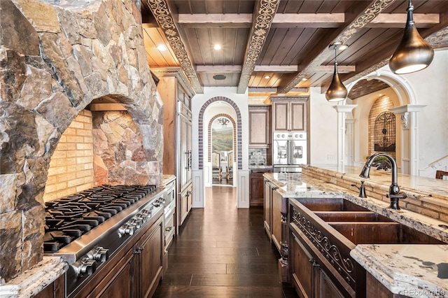 kitchen with hanging light fixtures, light stone countertops, sink, and stainless steel gas stovetop