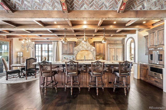 kitchen with a large island, double oven, a breakfast bar area, and light stone countertops