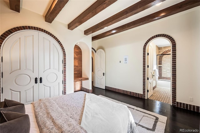 bedroom with a closet, ensuite bath, dark hardwood / wood-style floors, and beamed ceiling