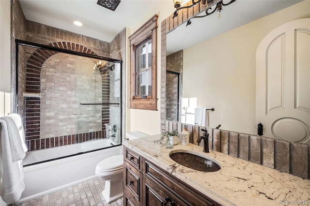 full bathroom with vanity, bath / shower combo with glass door, tile patterned floors, and toilet