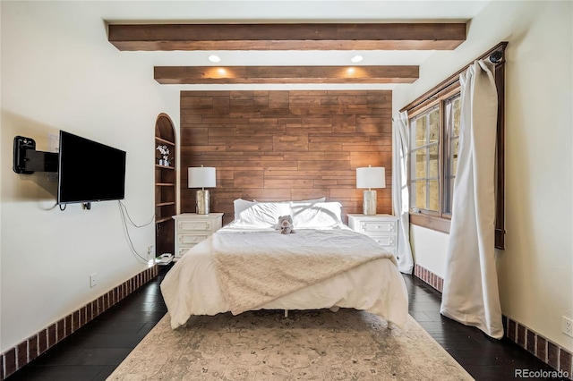 bedroom featuring beam ceiling, dark wood-type flooring, and wooden walls