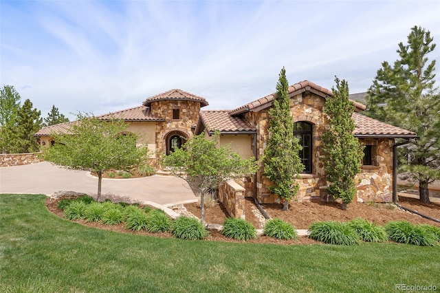 7188 Raphael Ln, Littleton, CO 80125 - mediterranean / spanish house featuring stone siding, a tiled roof, a front lawn, stucco siding, and driveway