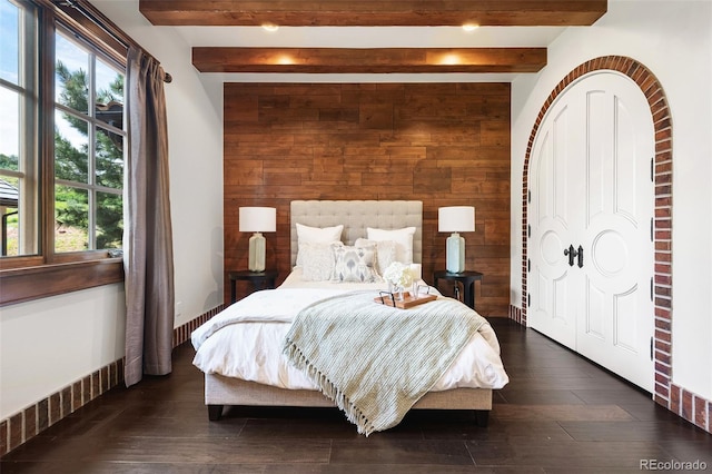 7188 Raphael Ln, Littleton, CO 80125 - bedroom featuring wooden walls, beamed ceiling, dark wood-style flooring, and an accent wall