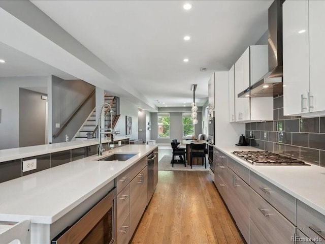 2508 S Pennsylvania St, Denver, CO 80210 - kitchen with a sink, stainless steel appliances, wall chimney exhaust hood, light countertops, and light wood finished floors