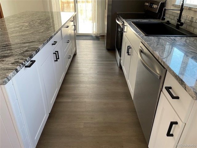 kitchen with tasteful backsplash, white cabinetry, appliances with stainless steel finishes, dark wood-style flooring, and a sink