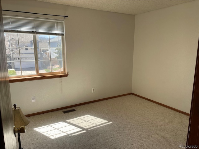 spare room featuring a textured ceiling, baseboards, visible vents, and carpet floors