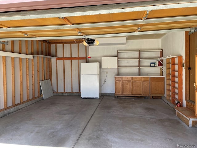 garage featuring a garage door opener and freestanding refrigerator