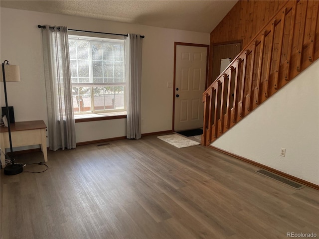 entrance foyer featuring stairway, visible vents, lofted ceiling, and wood finished floors