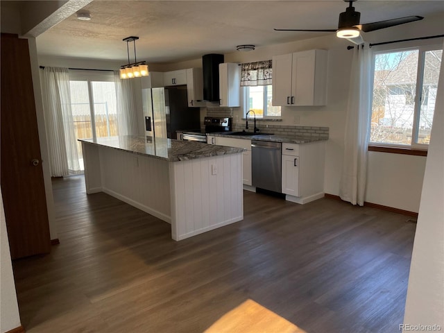 kitchen with dark wood finished floors, white cabinets, a center island, stainless steel appliances, and backsplash