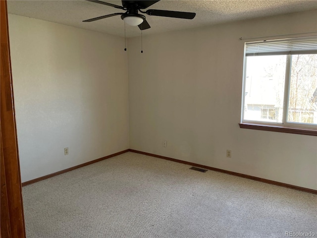 spare room featuring carpet floors, ceiling fan, baseboards, and a textured ceiling
