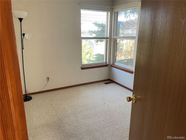 carpeted spare room featuring baseboards and visible vents