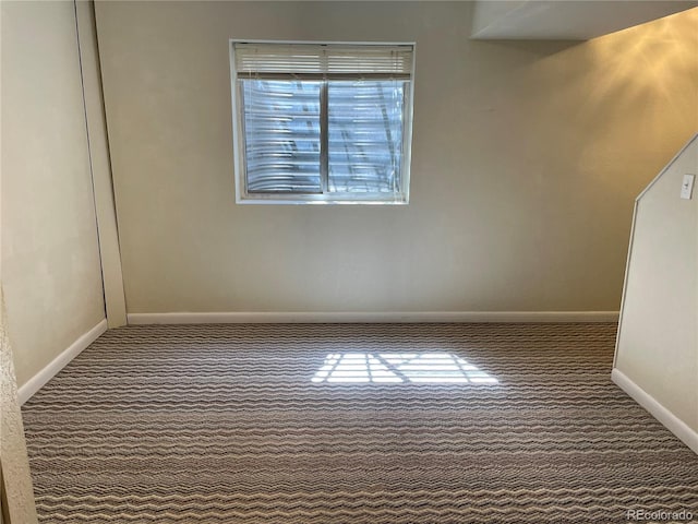 empty room featuring carpet and baseboards
