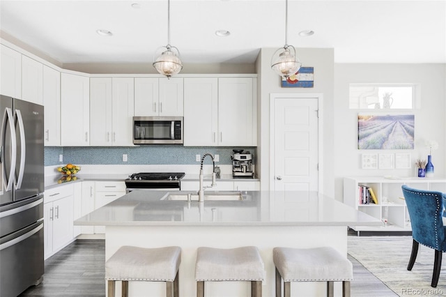 8917 Yates Dr, Westminster, CO 80031 - kitchen featuring appliances with stainless steel finishes, a sink, a breakfast bar, tasteful backsplash, and recessed lighting