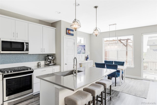8917 Yates Dr, Westminster, CO 80031 - kitchen with appliances with stainless steel finishes, a sink, wood finished floors, a kitchen breakfast bar, and recessed lighting