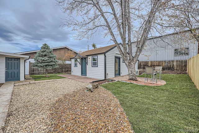 back of house featuring a fenced backyard, a lawn, a patio, and an outdoor structure