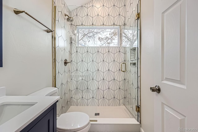 bathroom featuring toilet, a stall shower, and vanity