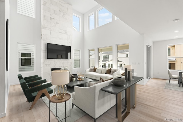 8850 Moonshimmer Trl, Littleton, CO 80125 - living room featuring healthy amount of natural light, light wood-style floors, a premium fireplace, and a high ceiling