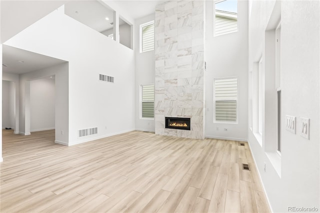 8850 Moonshimmer Trl, Littleton, CO 80125 - unfurnished living room featuring a towering ceiling, light wood-style floors, and a tile fireplace