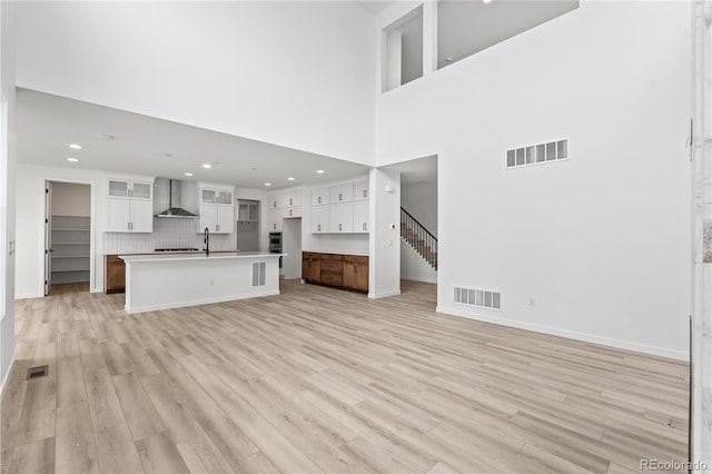 8850 Moonshimmer Trl, Littleton, CO 80125 - unfurnished living room featuring light wood-type flooring, recessed lighting, a towering ceiling, and stairs