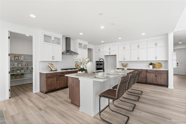 8850 Moonshimmer Trl, Littleton, CO 80125 - kitchen with wall chimney range hood, white cabinets, backsplash, light wood-type flooring, and recessed lighting