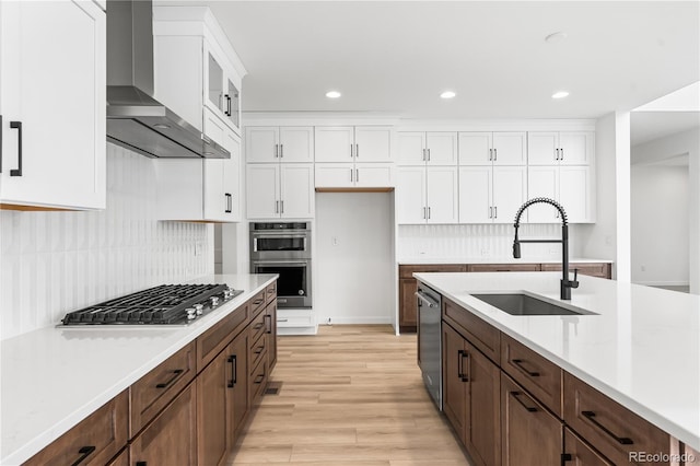 8850 Moonshimmer Trl, Littleton, CO 80125 - kitchen featuring wall chimney exhaust hood, stainless steel appliances, white cabinetry, light wood finished floors, and light countertops