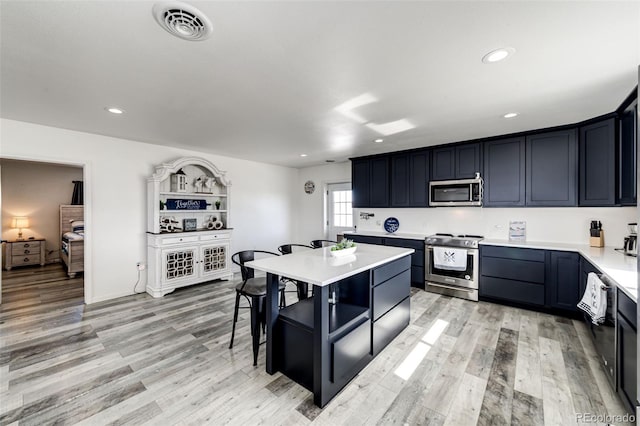 kitchen featuring appliances with stainless steel finishes, a center island, a breakfast bar area, and light hardwood / wood-style floors