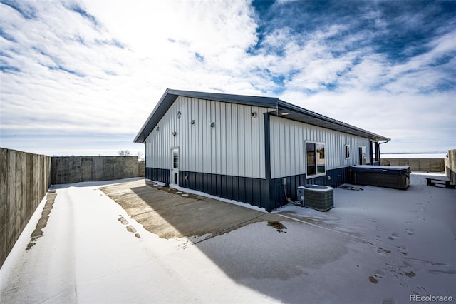 view of side of home with central AC unit and a hot tub