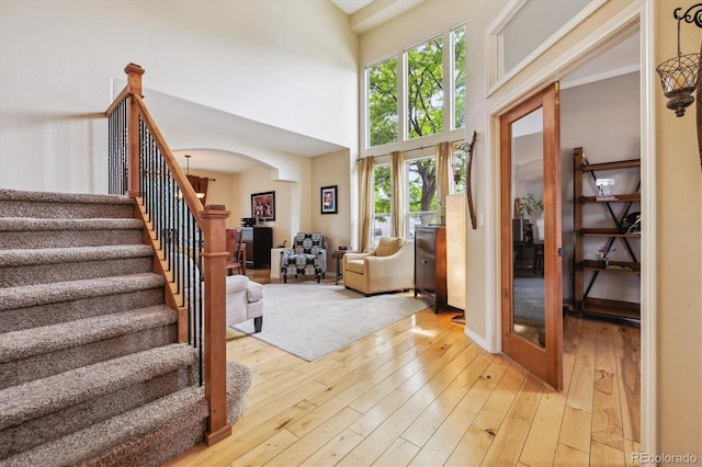9478 Burgundy Cir, Highlands Ranch, CO 80126 - foyer entrance with arched walkways, stairs, a towering ceiling, and light wood finished floors
