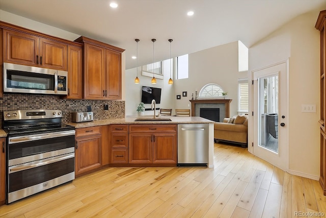 9478 Burgundy Cir, Highlands Ranch, CO 80126 - kitchen with stainless steel appliances, brown cabinets, open floor plan, and a fireplace