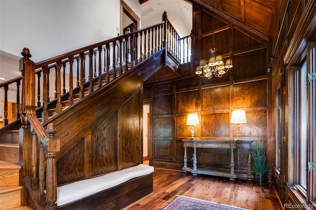 2409 E Cedar Ave, Denver, CO 80209 - stairs featuring a chandelier, hardwood / wood-style floors, wooden walls, and a high ceiling