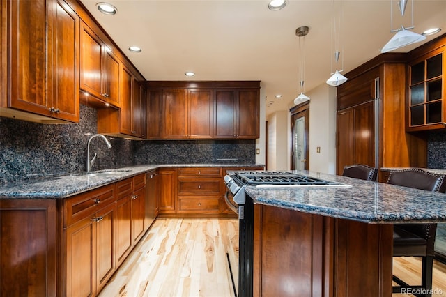 2409 E Cedar Ave, Denver, CO 80209 - kitchen with a breakfast bar, recessed lighting, light wood-style flooring, dark stone countertops, and appliances with stainless steel finishes