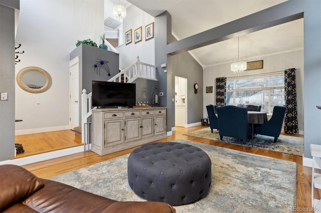 living room featuring ornamental molding, high vaulted ceiling, light hardwood / wood-style floors, and a notable chandelier