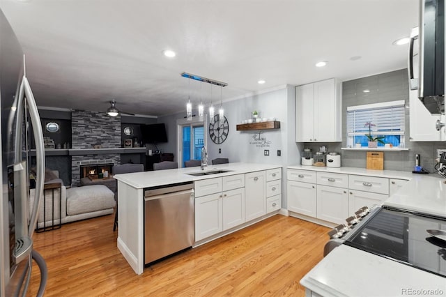 kitchen featuring pendant lighting, sink, stainless steel appliances, white cabinets, and kitchen peninsula