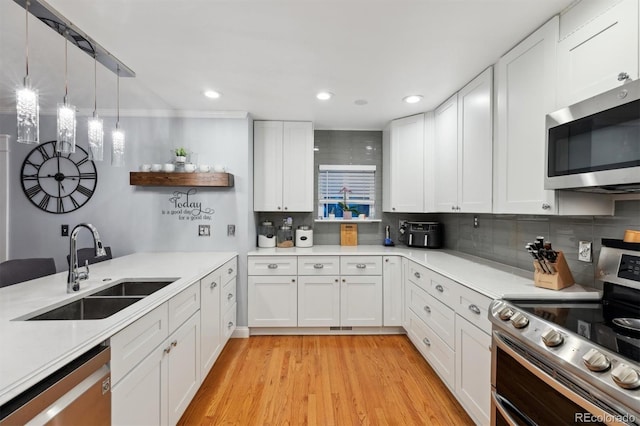 kitchen featuring hanging light fixtures, white cabinetry, appliances with stainless steel finishes, and sink