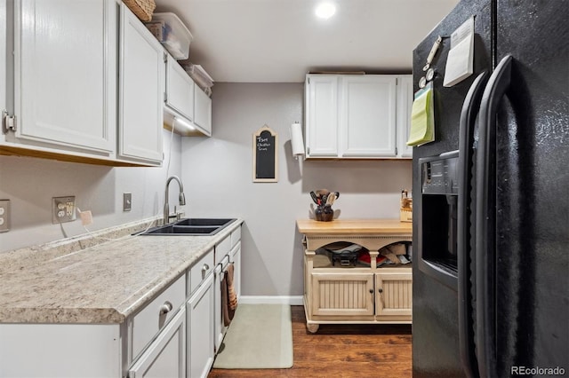 kitchen featuring dark hardwood / wood-style flooring, sink, black refrigerator with ice dispenser, and white cabinets