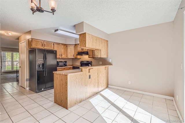 kitchen featuring a peninsula, a textured ceiling, light countertops, under cabinet range hood, and black appliances