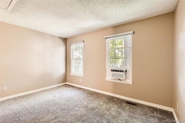 carpeted spare room featuring baseboards, a textured ceiling, and cooling unit
