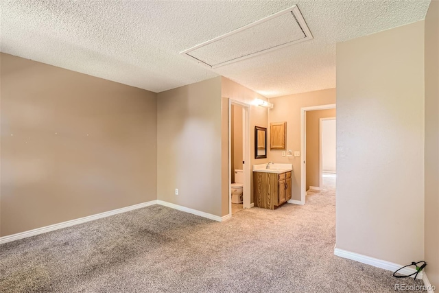 unfurnished room with light colored carpet, sink, and a textured ceiling