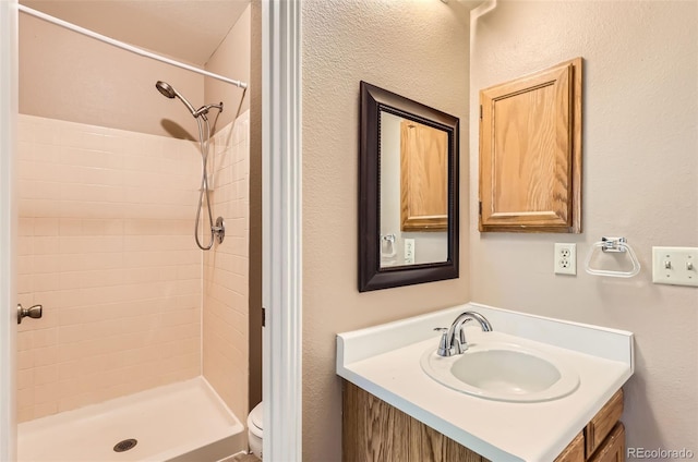 full bathroom featuring a stall shower, vanity, and toilet