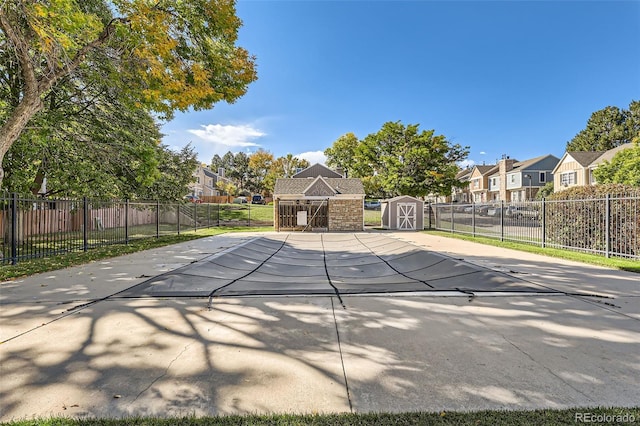 view of pool with an outdoor structure, fence, a fenced in pool, a residential view, and a storage unit