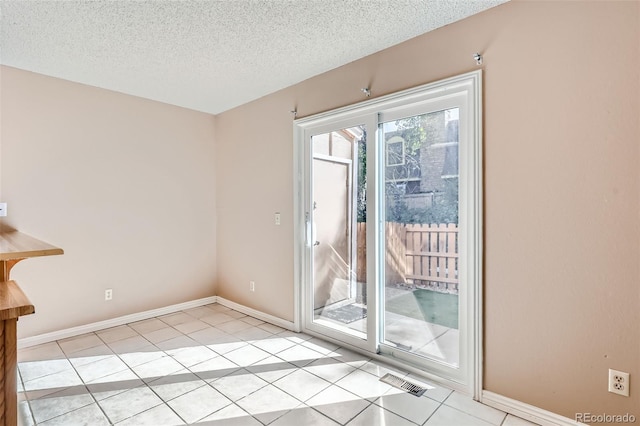 doorway to outside with light tile patterned flooring and a textured ceiling