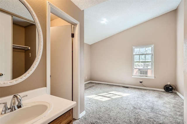 bathroom with vaulted ceiling, cooling unit, vanity, and a textured ceiling