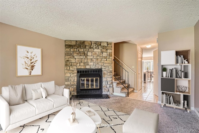 carpeted living room featuring stairway, a stone fireplace, and a textured ceiling