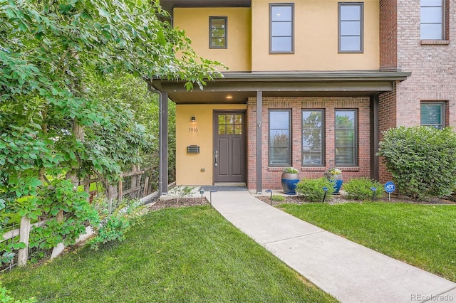 1916 S Elati St, Denver, CO 80223 - view of exterior entry with a yard, brick siding, stucco siding, and a porch