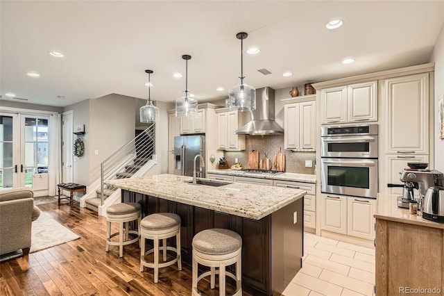 1916 S Elati St, Denver, CO 80223 - kitchen featuring wall chimney exhaust hood, stainless steel appliances, a kitchen breakfast bar, an island with sink, and backsplash