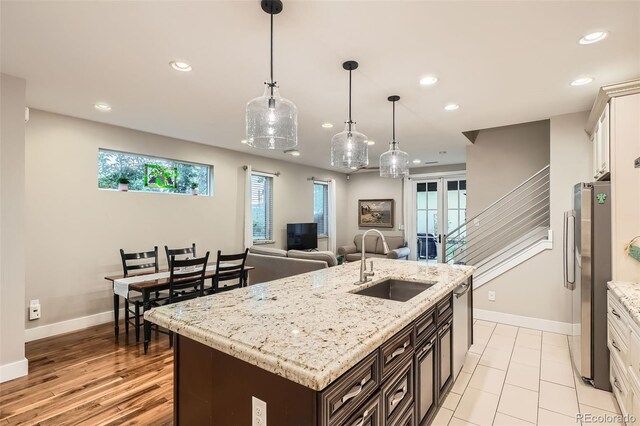 1916 S Elati St, Denver, CO 80223 - kitchen with stainless steel appliances, recessed lighting, a kitchen island with sink, light stone countertops, and decorative light fixtures