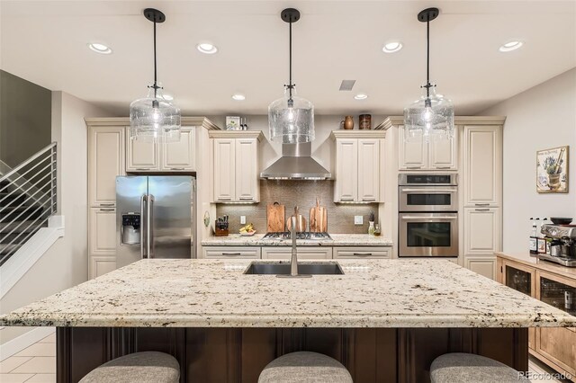 1916 S Elati St, Denver, CO 80223 - kitchen featuring appliances with stainless steel finishes, a kitchen bar, recessed lighting, backsplash, and light stone counters