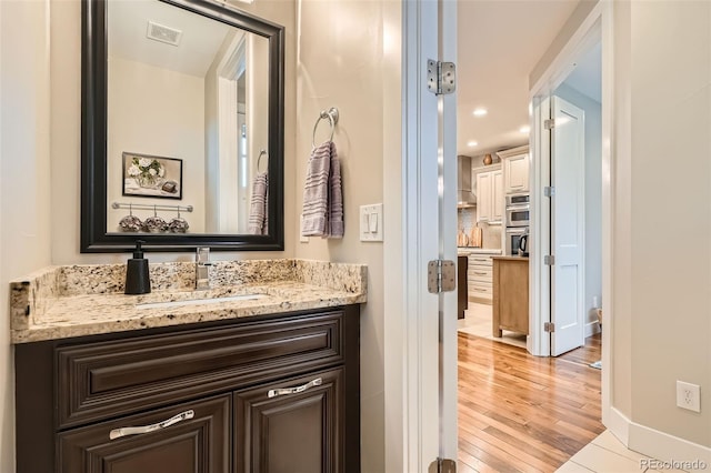 1916 S Elati St, Denver, CO 80223 - bathroom with vanity, wood finished floors, recessed lighting, and backsplash