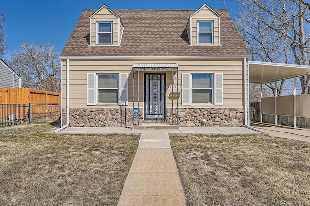 view of front of house featuring stone siding, a shingled roof, a front lawn, and fence